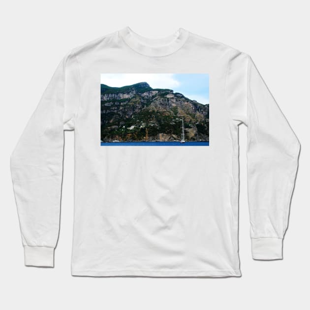 View in Amalfi coast at a huge mountain with rocky parts, greenery and buildings with a white boat underneath Long Sleeve T-Shirt by KristinaDrozd